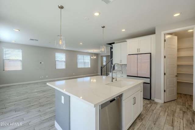 kitchen with white cabinetry, a center island with sink, hanging light fixtures, and sink