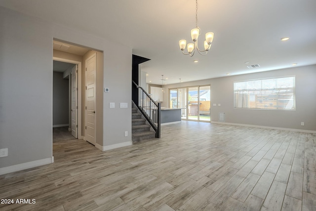 unfurnished living room featuring a chandelier and light hardwood / wood-style floors