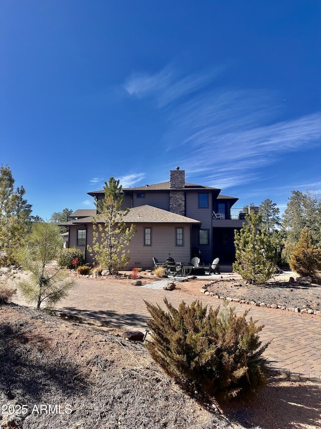 rear view of property featuring a chimney, a patio area, and a balcony