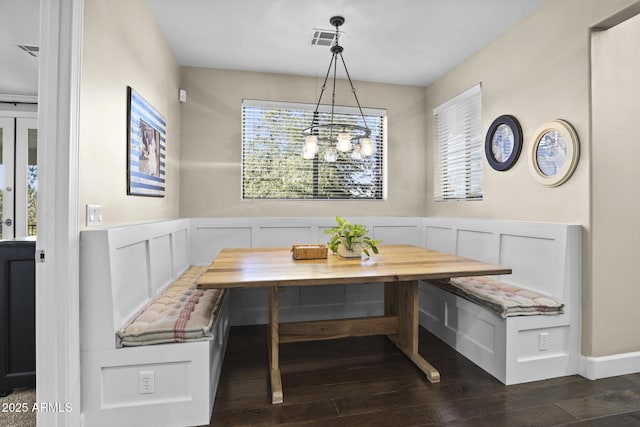 dining space featuring dark wood-style flooring, breakfast area, visible vents, and a decorative wall