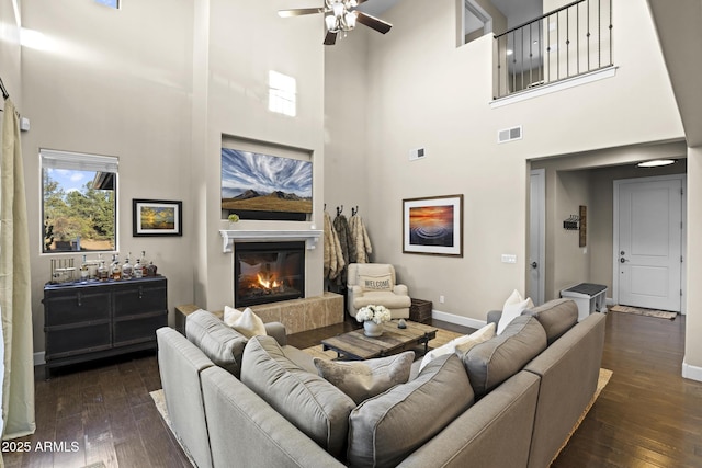 living room featuring dark wood-style floors, baseboards, visible vents, and a glass covered fireplace