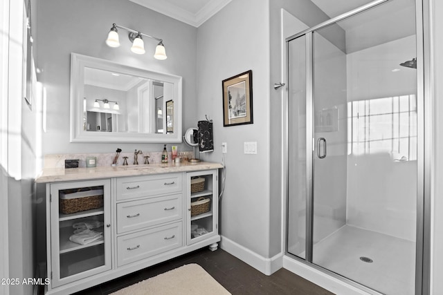 bathroom with crown molding, a shower stall, vanity, wood finished floors, and baseboards