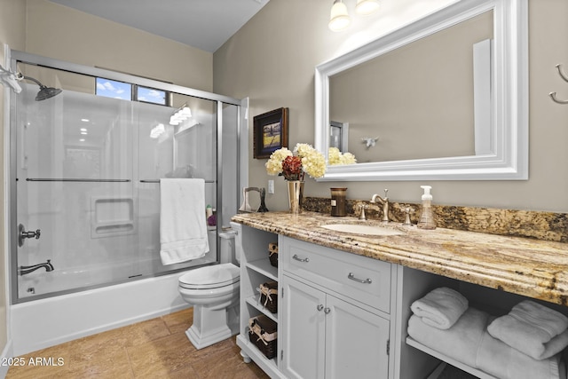 full bathroom featuring enclosed tub / shower combo, vanity, and toilet