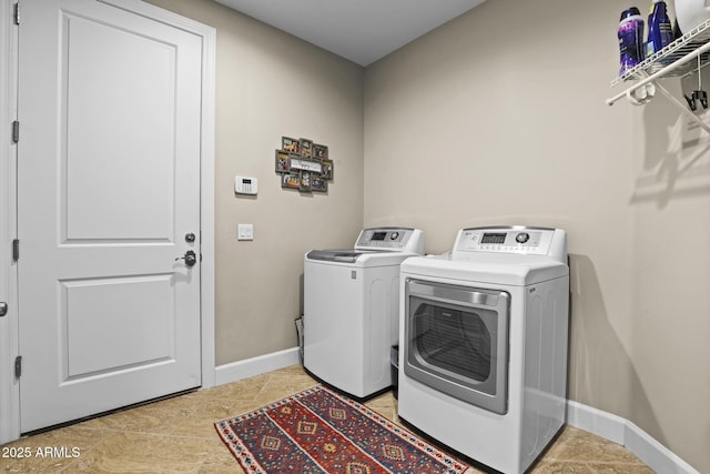 washroom featuring laundry area, washing machine and dryer, and baseboards