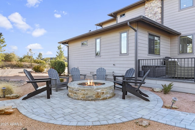 rear view of property featuring an outdoor fire pit, stone siding, and a patio area