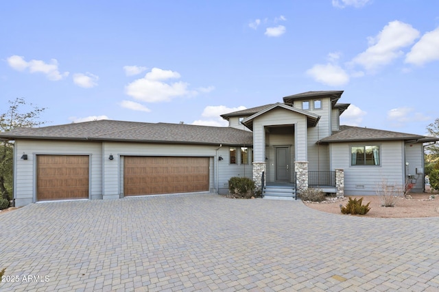 prairie-style home with a garage, stone siding, and decorative driveway