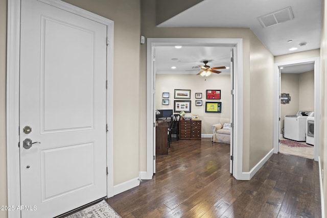 hallway featuring dark wood-style flooring, washer and clothes dryer, visible vents, and baseboards