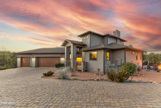 prairie-style home featuring decorative driveway, a chimney, and an attached garage