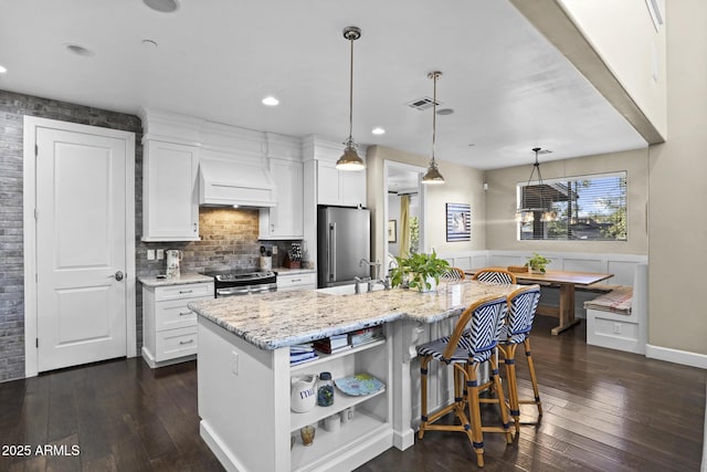 kitchen featuring appliances with stainless steel finishes, breakfast area, white cabinets, and custom exhaust hood