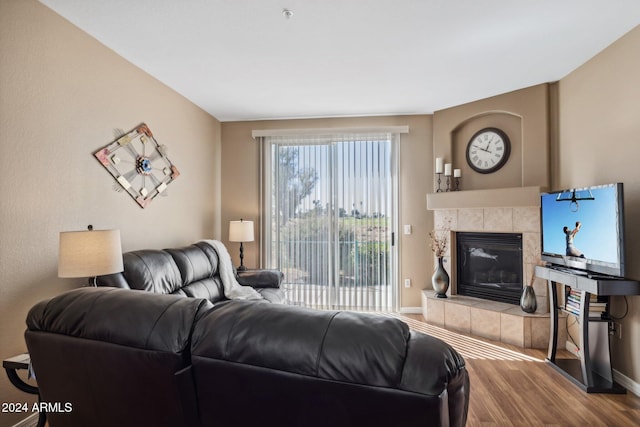 living room featuring a tiled fireplace and hardwood / wood-style flooring