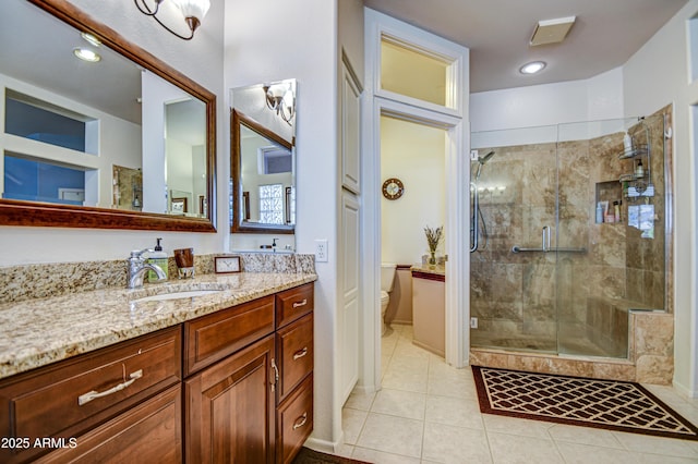 bathroom with toilet, tile patterned floors, vanity, and a shower with shower door