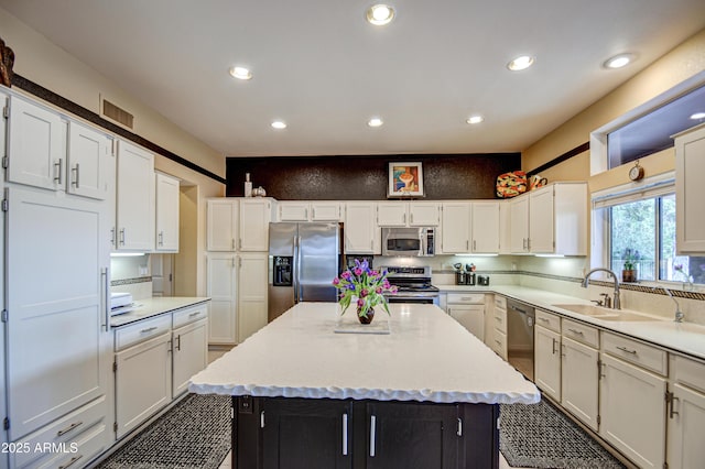 kitchen with white cabinets, appliances with stainless steel finishes, sink, and a kitchen island