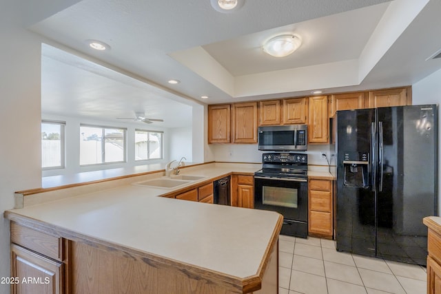 kitchen with a raised ceiling, kitchen peninsula, sink, and black appliances