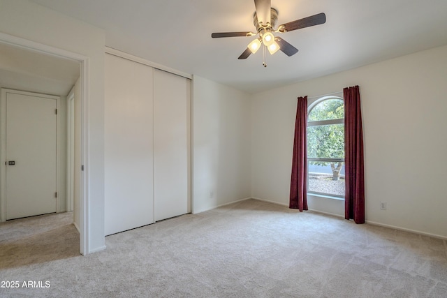 unfurnished bedroom with a closet, ceiling fan, and light colored carpet