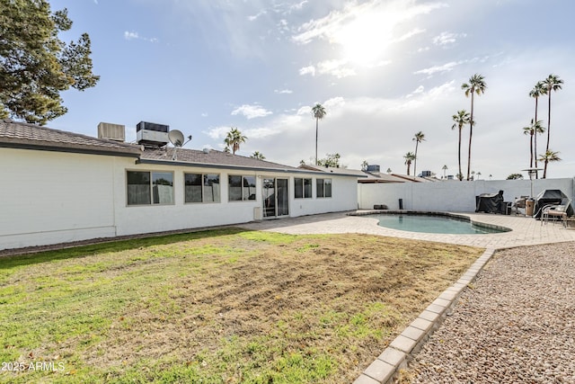 back of property with a fenced in pool, a patio area, and a lawn