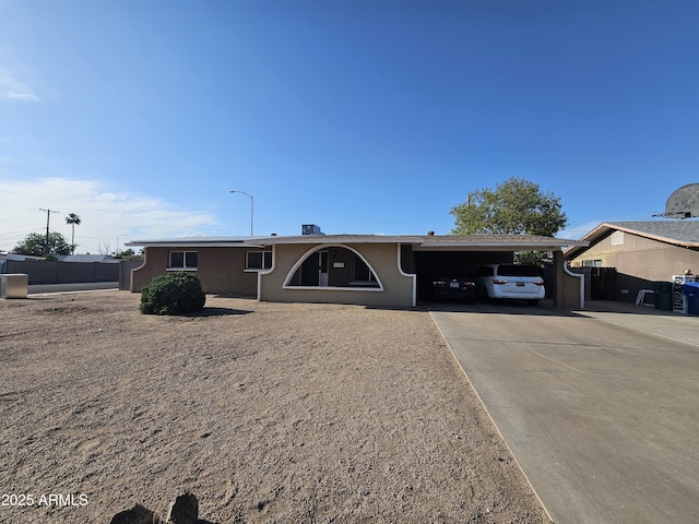 single story home featuring stucco siding, fence, driveway, and an attached carport