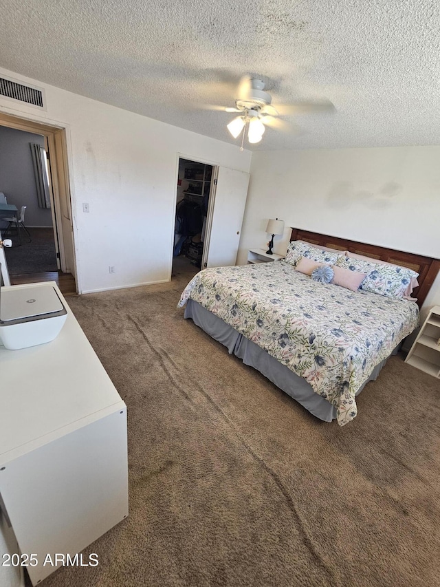 carpeted bedroom featuring ceiling fan, a closet, a textured ceiling, and visible vents