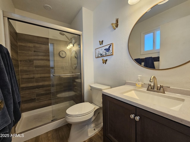 full bath with vanity, a stall shower, toilet, and wood finished floors