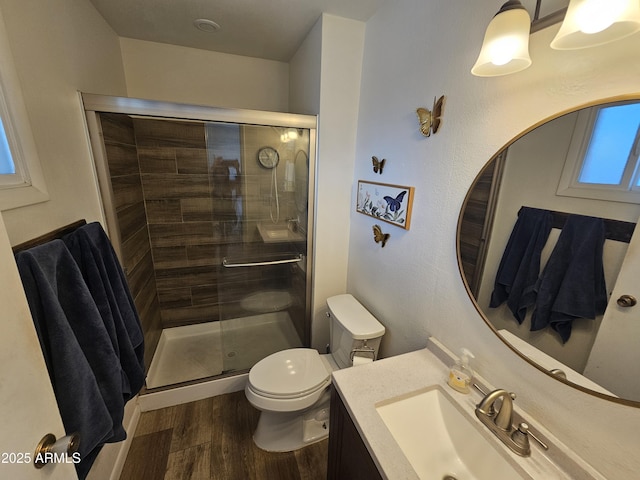 full bath with vanity, a stall shower, toilet, and wood finished floors