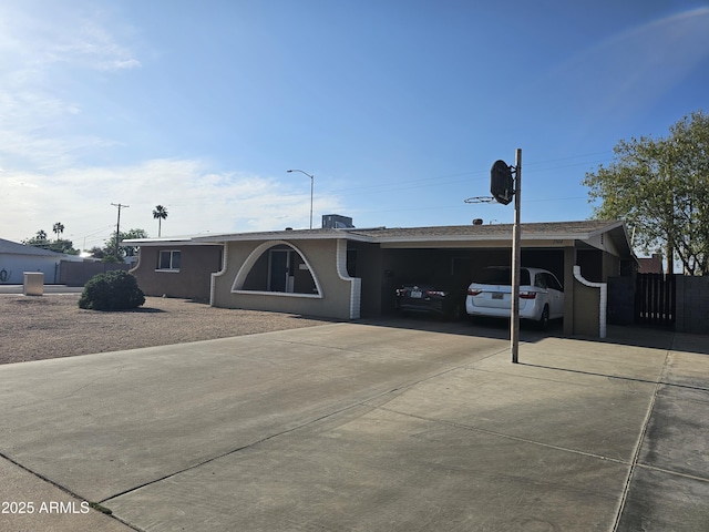 single story home featuring fence, an attached carport, stucco siding, and concrete driveway