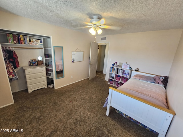 carpeted bedroom with ceiling fan, a textured ceiling, visible vents, baseboards, and a closet
