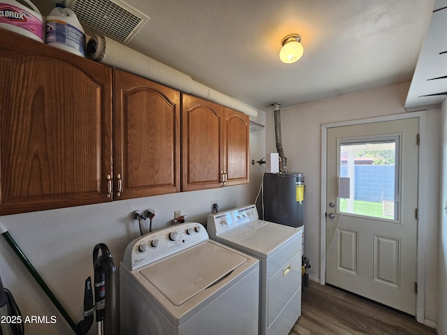 laundry area featuring cabinet space, water heater, visible vents, dark wood-style floors, and washer and clothes dryer