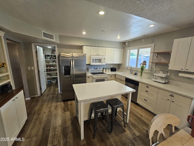kitchen with a sink, stainless steel appliances, dark wood-type flooring, and visible vents