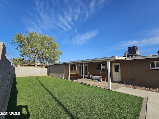 back of property with a fenced backyard, a yard, a patio area, and central AC