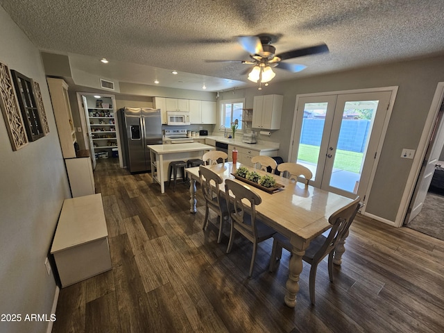 dining area with visible vents, a textured ceiling, french doors, a ceiling fan, and dark wood finished floors