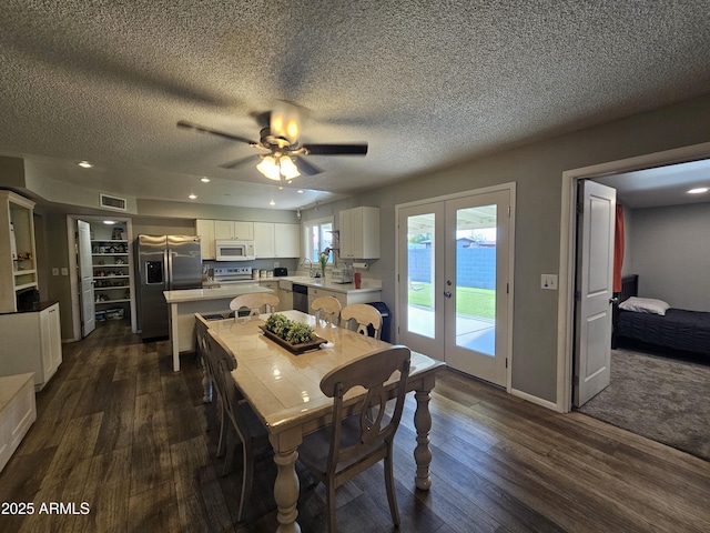dining space with a ceiling fan, french doors, dark wood-style flooring, a textured ceiling, and visible vents