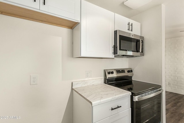 kitchen with dark wood-style floors, appliances with stainless steel finishes, and white cabinets