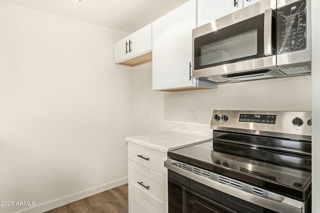 kitchen featuring stainless steel appliances, white cabinets, baseboards, and wood finished floors