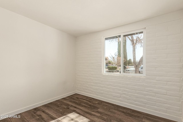 spare room featuring dark wood-style flooring and baseboards