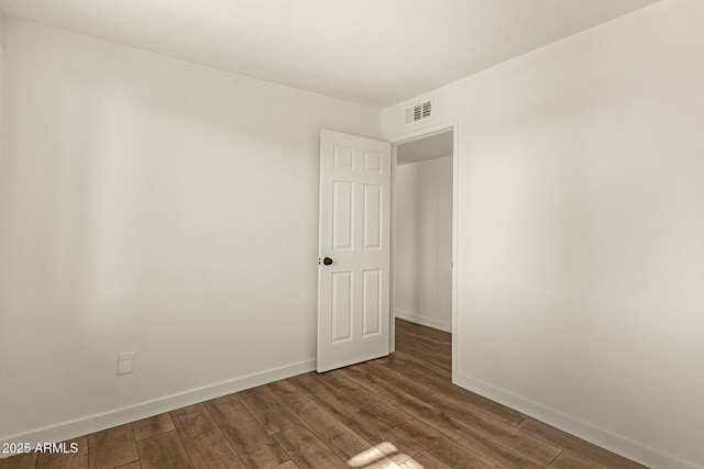 unfurnished room featuring baseboards, visible vents, and wood finished floors