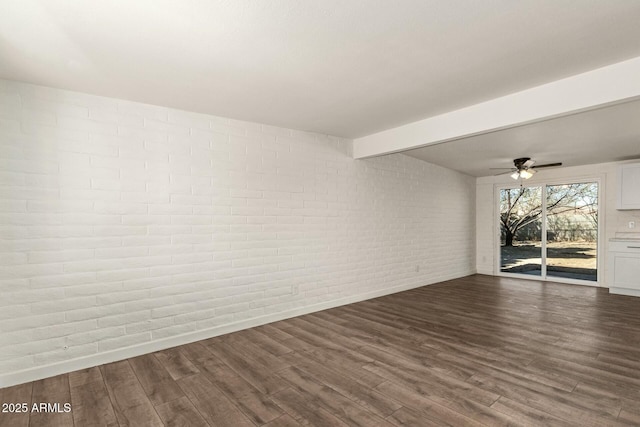 empty room with brick wall, dark wood-type flooring, beamed ceiling, and a ceiling fan