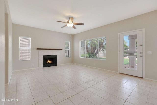 unfurnished living room with ceiling fan, a tile fireplace, and light tile patterned floors