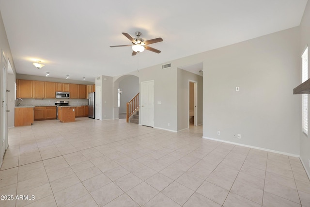 unfurnished living room with sink, light tile patterned floors, and ceiling fan