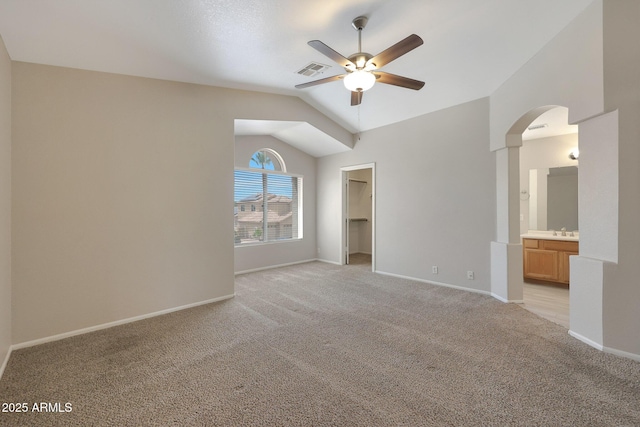 unfurnished bedroom featuring lofted ceiling, sink, ensuite bath, a spacious closet, and light colored carpet