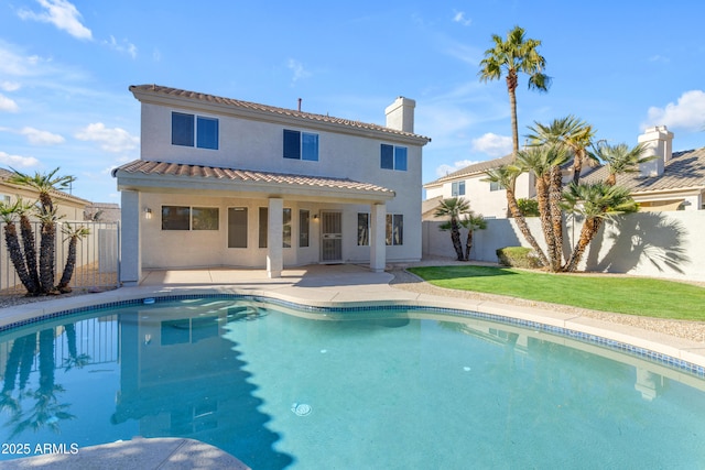 rear view of property featuring a fenced in pool and a patio area