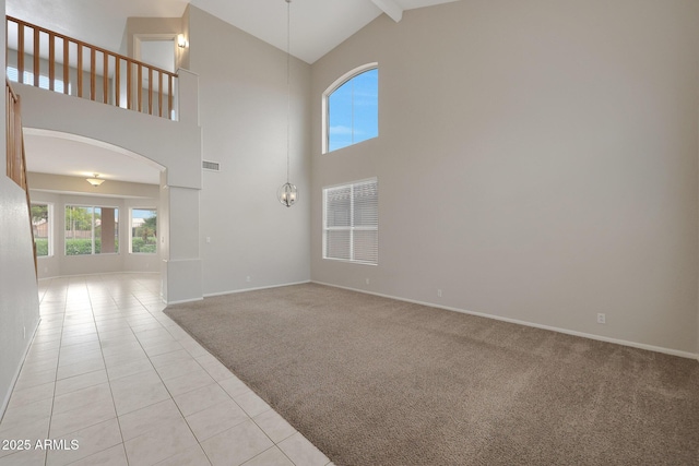 unfurnished living room with light colored carpet, high vaulted ceiling, and a notable chandelier