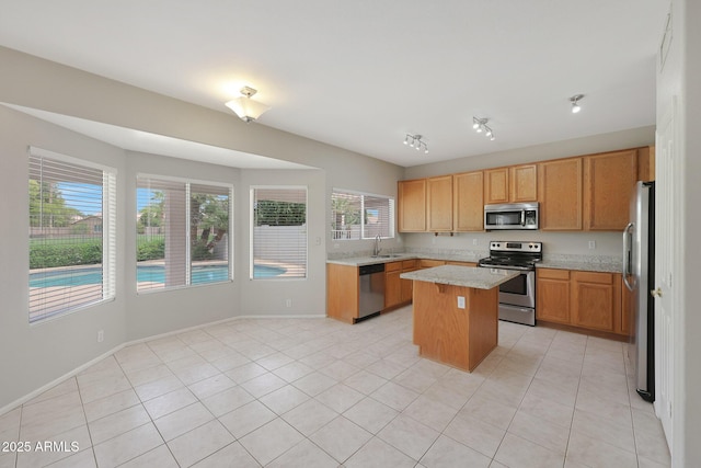 kitchen featuring light stone counters, light tile patterned floors, a center island, and appliances with stainless steel finishes