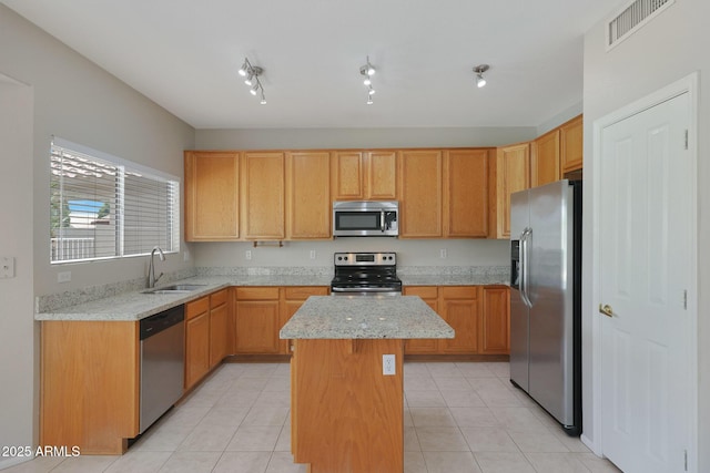 kitchen with stainless steel appliances, a center island, sink, and light stone countertops