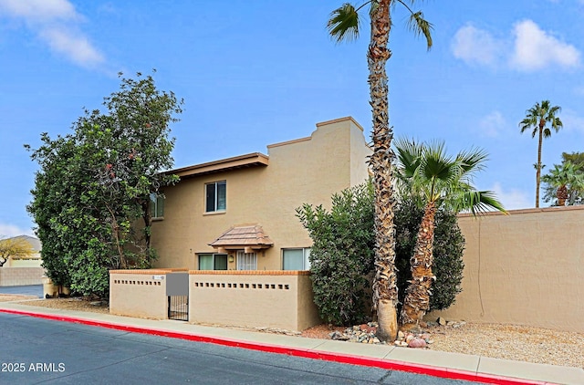 view of front facade with a fenced front yard, a gate, and stucco siding