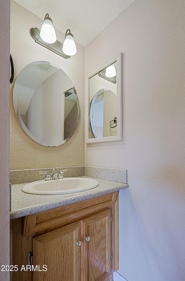 bathroom with a textured wall and vanity