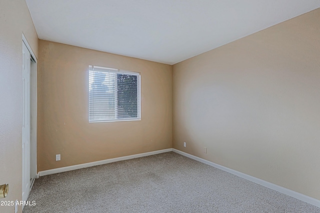 carpeted spare room featuring baseboards