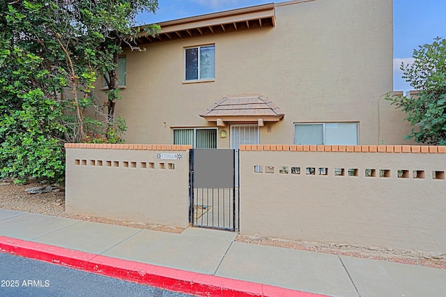 view of property with a fenced front yard, a gate, and stucco siding