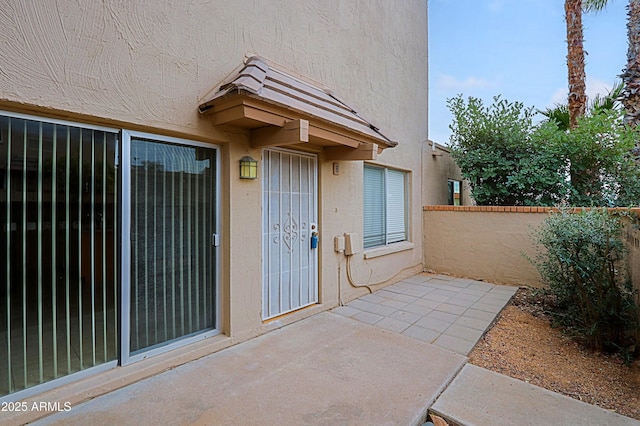 doorway to property featuring a patio area, fence, and stucco siding