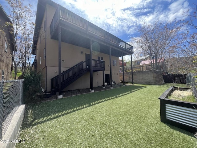 back of house with stairway, a yard, fence, and stucco siding