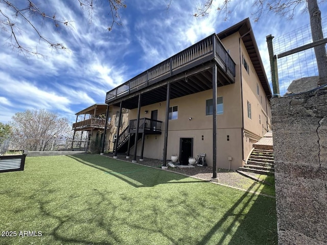 rear view of house featuring stairs, a yard, and stucco siding