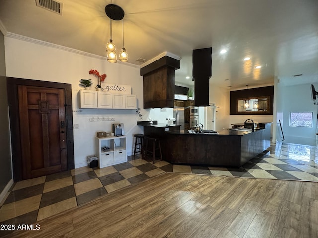 kitchen featuring appliances with stainless steel finishes, visible vents, a peninsula, and wood finished floors